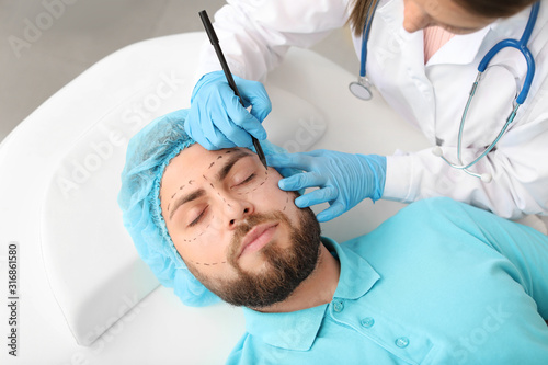 Plastic surgeon applying ma...