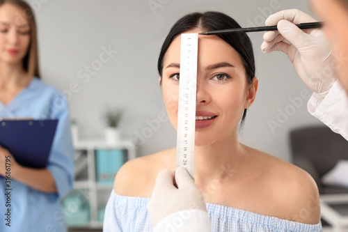 Plastic surgeon examining y...