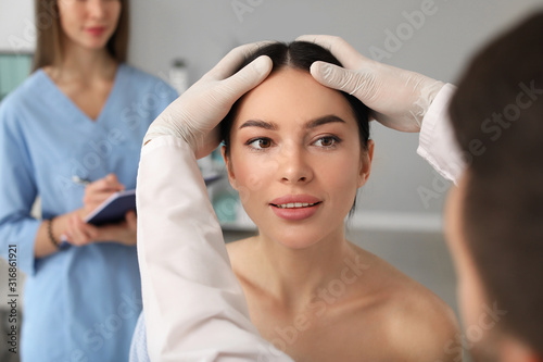 Plastic surgeon examining y...