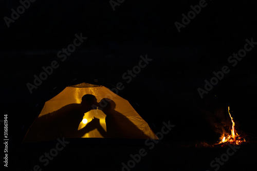 Shadow of a couple in love kisses in a tourist tent in nature. camping in the wilderness