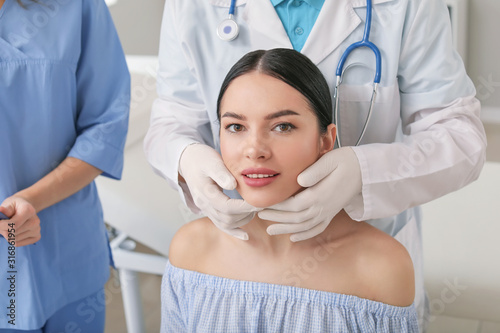 Plastic surgeon examining y...
