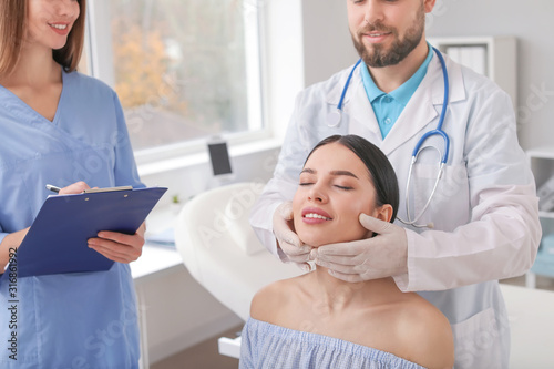 Plastic surgeon examining y...