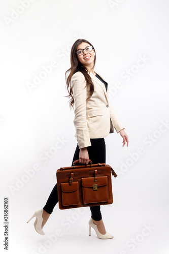 Young enthusiastic businesswoman walking and carrying brown leather satchel isolated white background