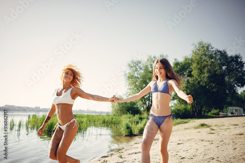 Family near a lake. Beautiful mother with cute daughter. Girls in a stylish swimsuits