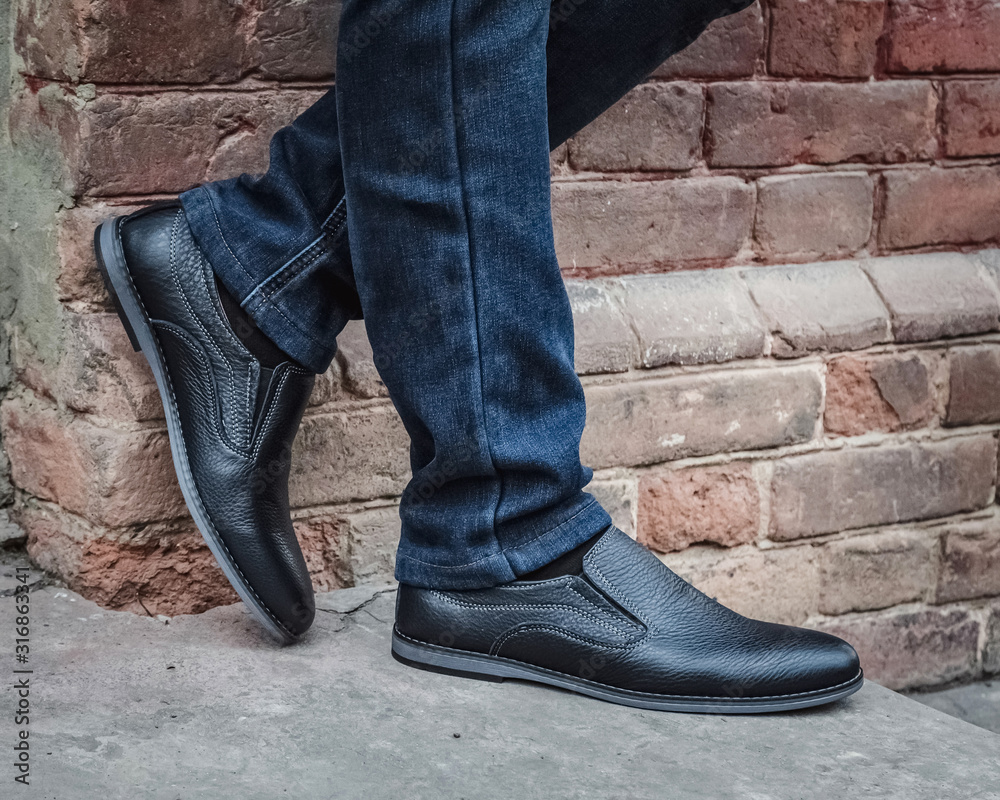 Close up on man's legs wearing blue jeans and blue shoes.