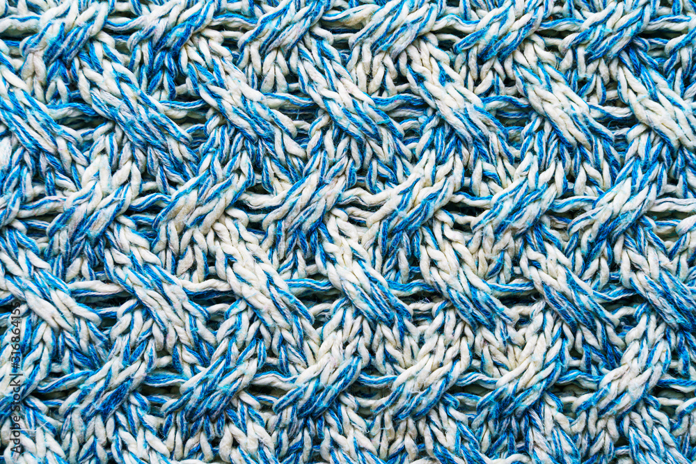 Blue and white texture of a knitted woolen fabric with a patterned weave. Sweater background Blue and white texture of a knitted woolen fabric with a patterned weave. Sweater background