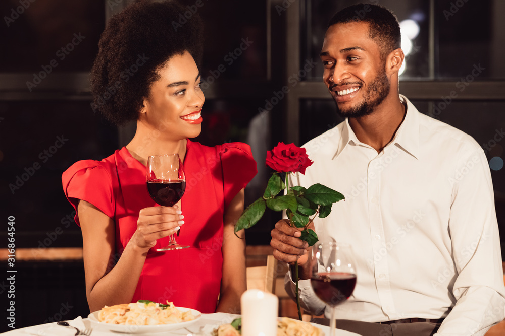 Man Giving Rose To Woman Having Valentine's Date In Restaurant Man Giving Rose To Woman Having Valentine's Date In Restaurant