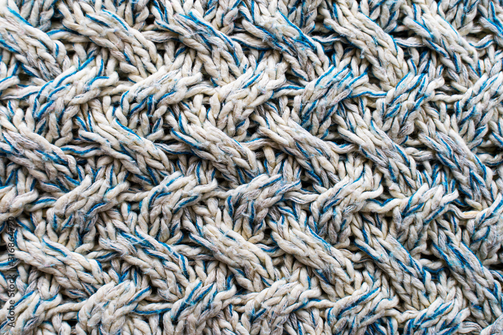 Blue and white texture of a knitted woolen fabric with a patterned weave. Sweater background