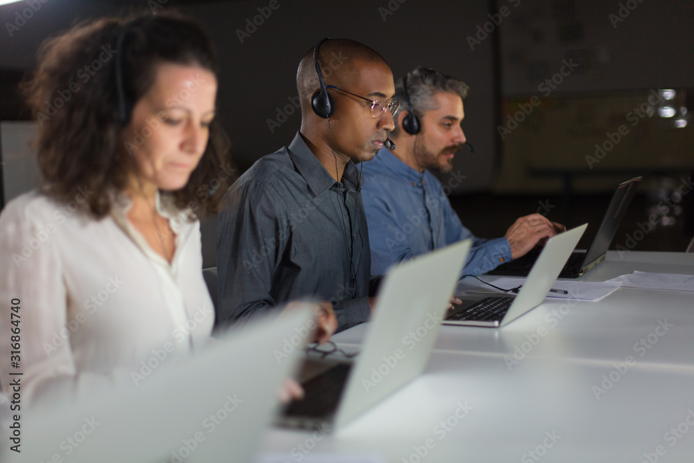 Confident client support team at workplace. Thoughtful call center operators during working process. Call center concept Confident client support team at workplace. Thoughtful call center operators during working process. Call center concept