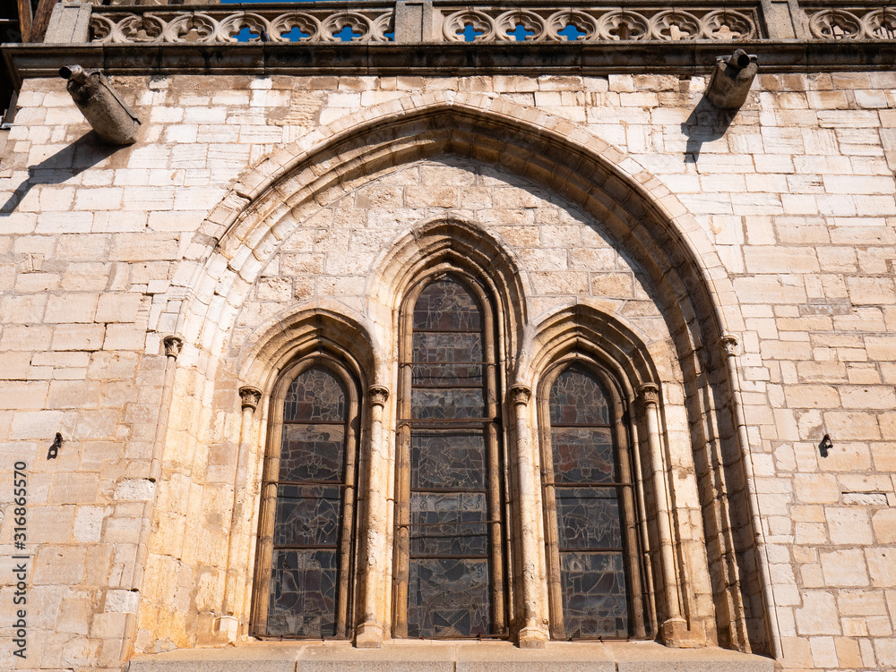 Stained glass windows of a cathedral seen from the outside in an ogival arch on a stone facade