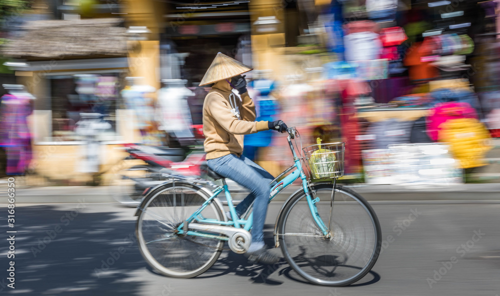 Panning motion shot of commuter in Hoi An, Vietnam.