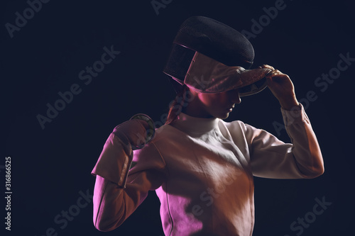 Young female fencer on dark background photo