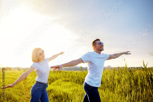 holidays, vacation, love and friendship. smiling couple in white T-shirts, sunglasses and jeans spread apart arms mimicking airplanes. Summer. Vacation air travel concept.