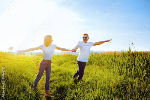 holidays, vacation, love and friendship. smiling couple in white T-shirts, sunglasses and jeans spread apart arms mimicking airplanes. Summer. Vacation air travel concept. © zamuruev