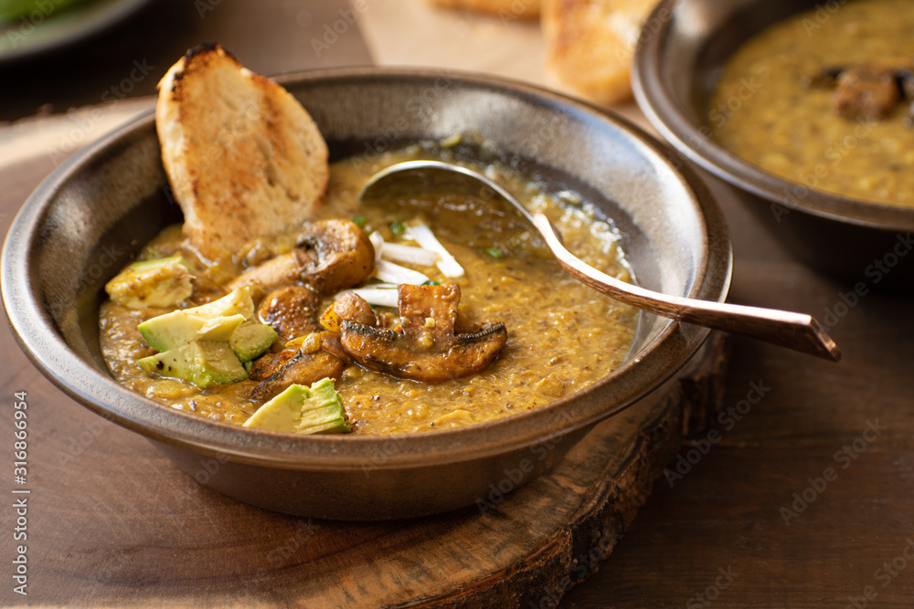 Vegan cream of mushroom soup on wooden table along with toasted bread and avocado Vegan cream of mushroom soup on wooden table along with toasted bread and avocado
