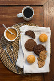 A top view of some sweet biscuits, black coffee and brown sugar on a wooden table