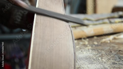 Craftman making guitar using chisel on wood photo