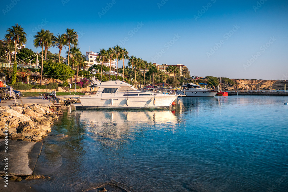 Boats in bay at background of coastline with palms, Cyprus vacation concept.