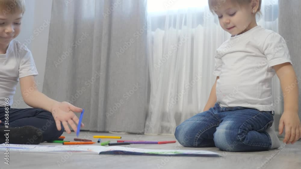 children draw with felt-tip pens in an album. little boy and girl concept childhood brother and sister play lifestyle paint on floor with colored markers children draw with felt-tip pens in an album. little boy and girl concept childhood brother and sister play lifestyle paint on floor with colored markers