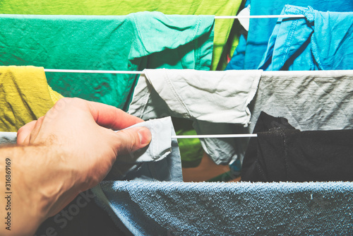 Stacking clothes on the dryer. Clothes drying concept. A man hangs laundry on the dryer, attention to order and cleanliness in the apartment.