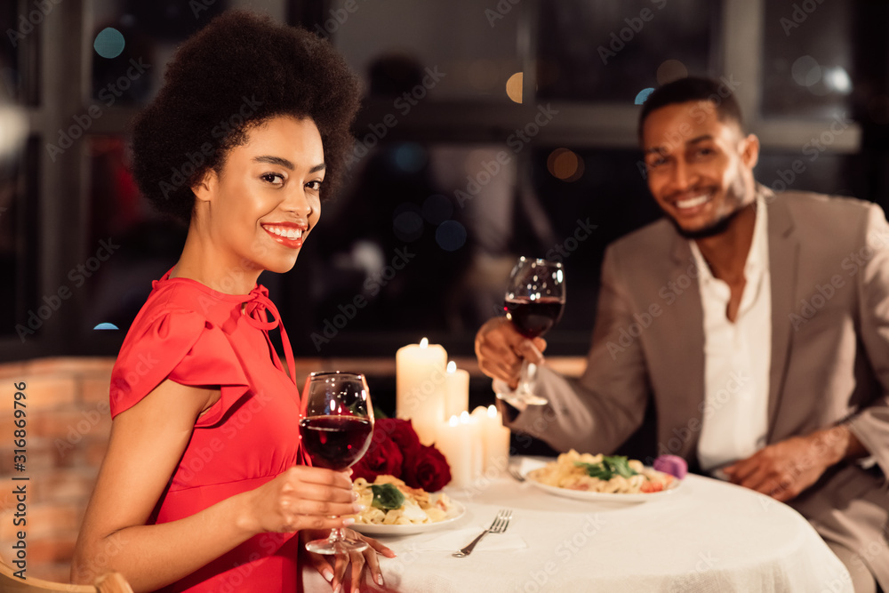 Couple Holding Glasses Smiling To Camera Sitting In Fancy Restaurant