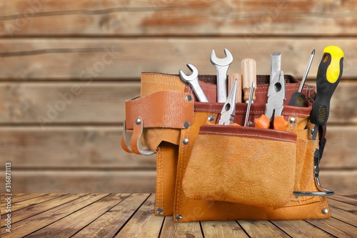 Tool belt with tools on wooden background photo