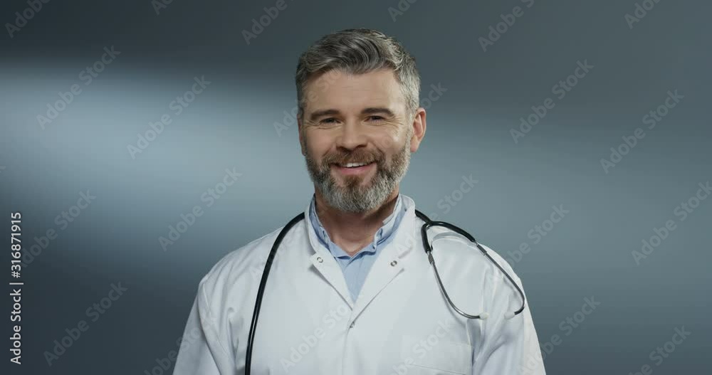 Caucasian happy good looking man surgeon taking off blue mask of his mouth and smiling cheerfully. Portrait. Close up. Caucasian happy good looking man surgeon taking off blue mask of his mouth and smiling cheerfully. Portrait. Close up.
