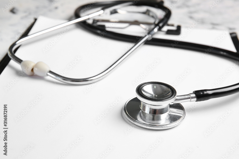 Stethoscope and clipboard on table, closeup Stethoscope and clipboard on table, closeup