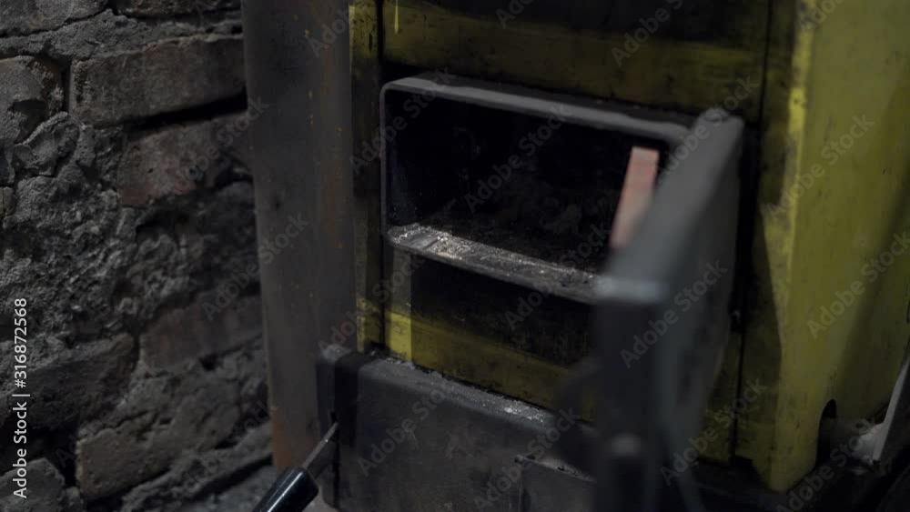 Man is cleaning coal stove in the basement using Iron Ash Rake Man is cleaning coal stove in the basement using Iron Ash Rake