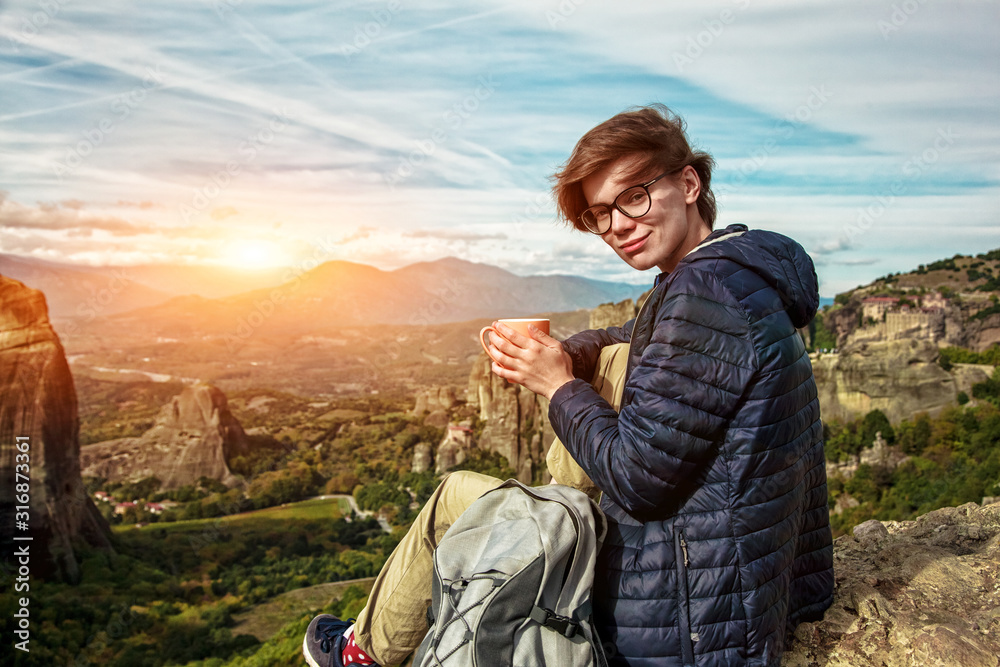 woman with cup of coffee resting and enjoying scenery on mountain