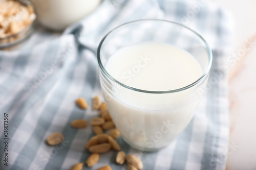 Glass of tasty peanut milk on white table