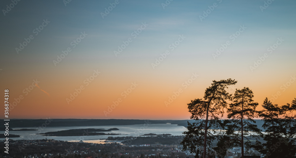 Widok na stolicę Norwegii w Oslo tuż po zachodzie słońca w kierunku Oslofjordu - obrazy, fototapety, plakaty 