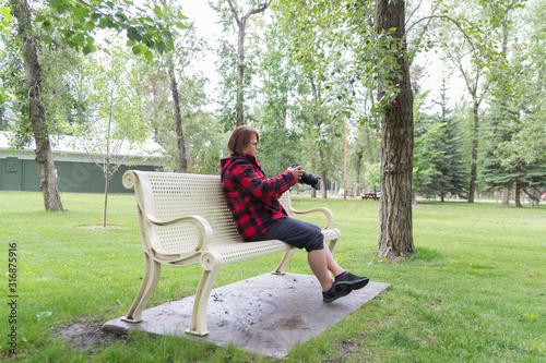 woman sitting on a park bench with a camera in hand