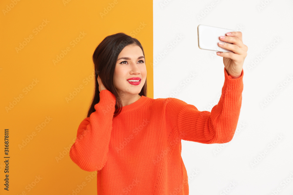 Beautiful young woman taking selfie on color background Beautiful young woman taking selfie on color background
