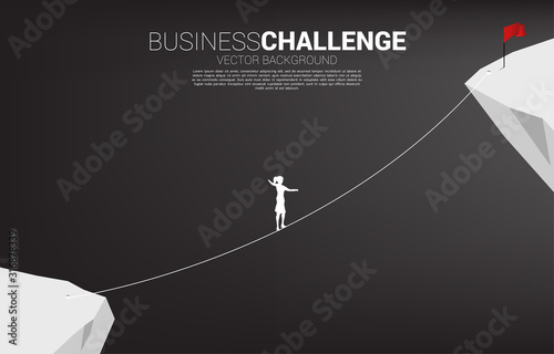 Silhouette of businesswoman walking on rope walk way to red flag.Concept for business risk and challenge in career path