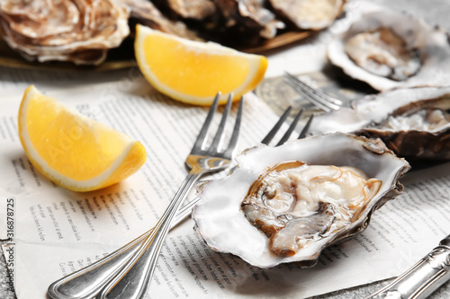 Tasty oysters with lemon on table