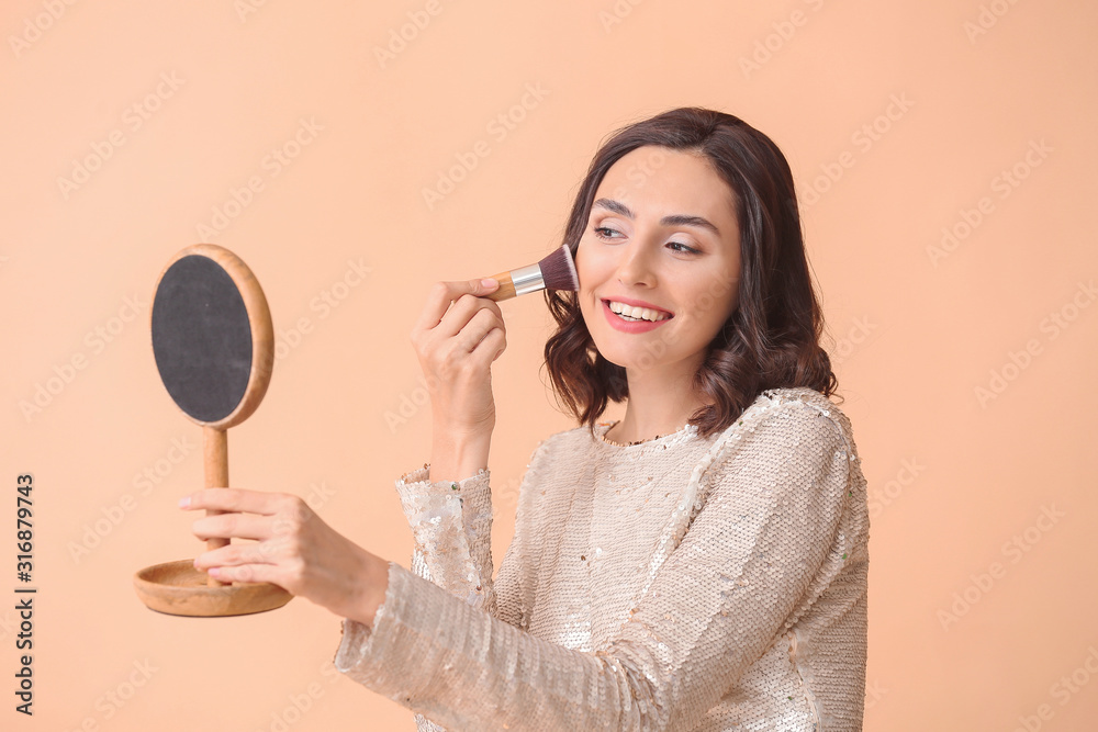 Beautiful young woman applying makeup on color background Beautiful young woman applying makeup on color background
