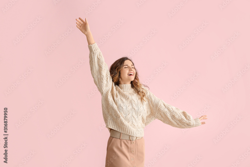 Beautiful young woman in warm sweater on color background