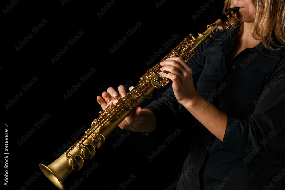 Naklejka premium soprano saxophone in hands on a black background