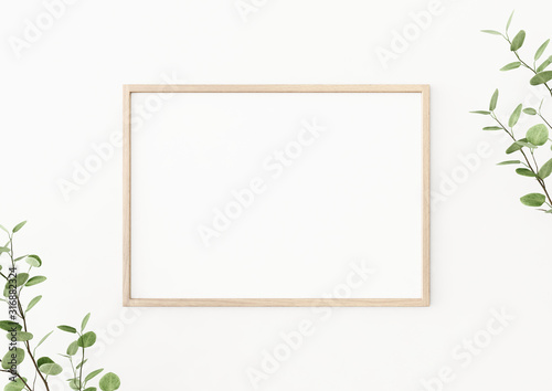 Interior poster mockup with horizontal wooden frame on empty white wall, decorated with plant branches with green leaves. A4, A3 size format. 3D rendering, illustration.