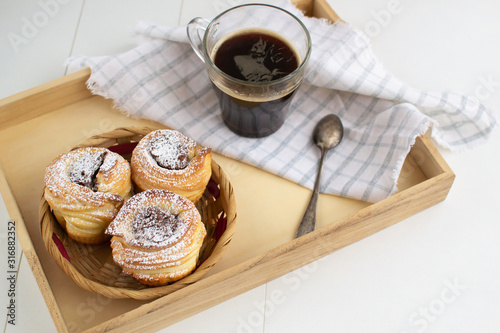 Cruffins with nut paste filling with a cup of espresso on a wooden tray.