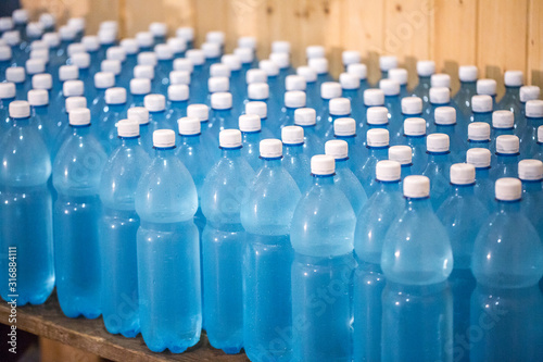 Production of mineral water on a small family business. The water is poured into plastic 1.5 liter PETE bottles. Many unlabeled bottles, swirled with white lids, stand on the table.