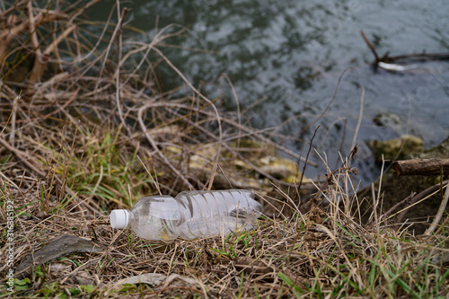 Fototapeta Naklejka Na Ścianę i Meble -  plastic bottle on the shore by the water
