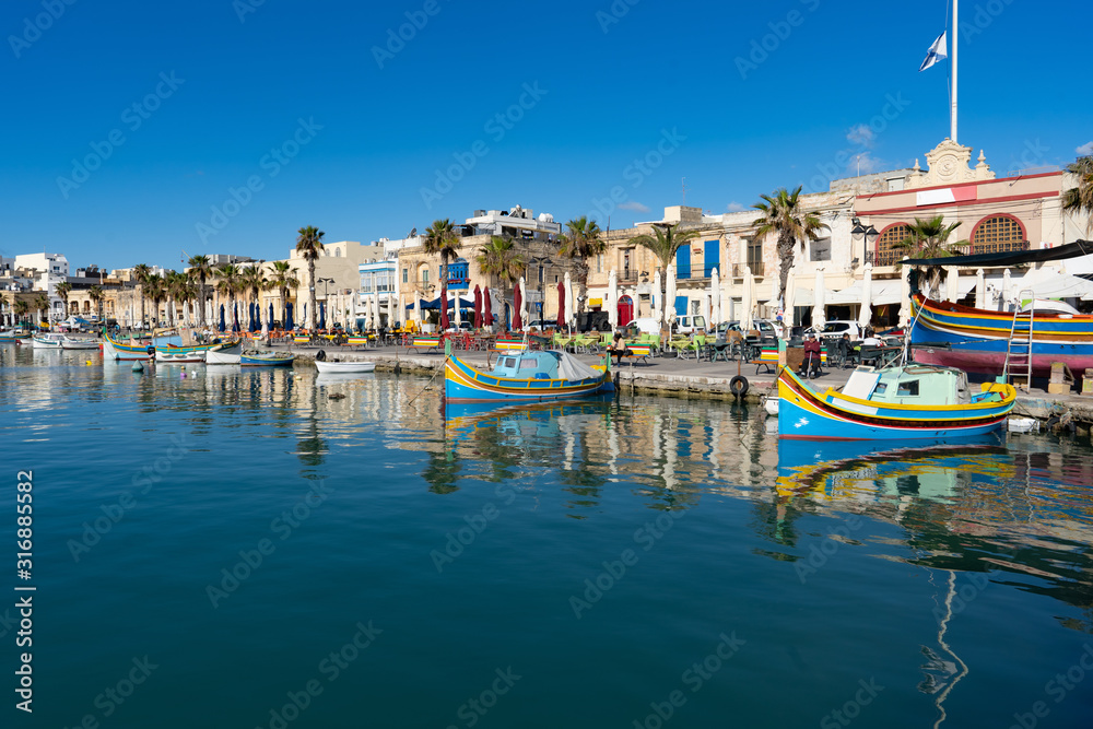 Mediterranean traditional colorful boats luzzu. Fisherman village in the south east of Malta. Early summer morning in Marsaxlokk, Malta