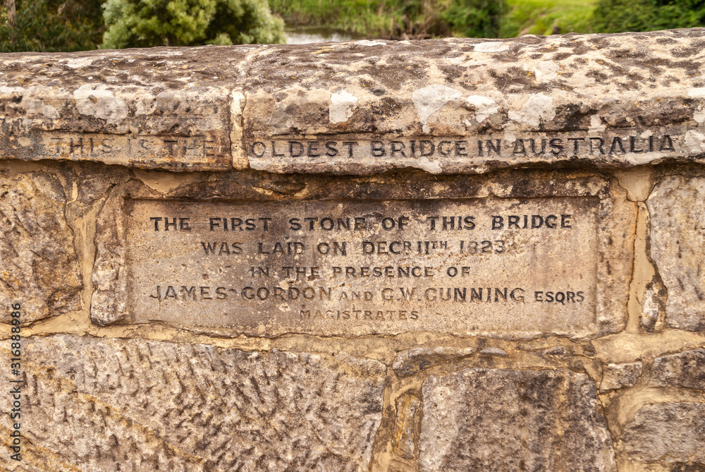 Richmond, Tasmania, Australia - December 13, 2009: Closeup of inscription on brown stone historic bridge over coal river with., naming it the oldest bridge in Australia.