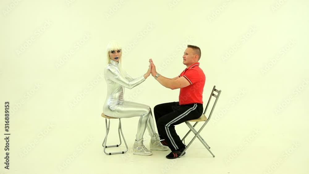 Robot girl or doll or alien with man, having fun, playing game, sitting Robot girl or doll or alien with man, having fun, playing game, sitting