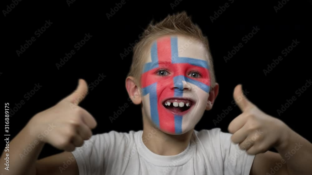 Happy boy rejoices victory of his favorite team of Faroe Islands. A child with a face painted in national colors. Portrait of a happy young fan. Joyful emotions and gestures. Victory. Triumph. Happy boy rejoices victory of his favorite team of Faroe Islands. A child with a face painted in national colors. Portrait of a happy young fan. Joyful emotions and gestures. Victory. Triumph.