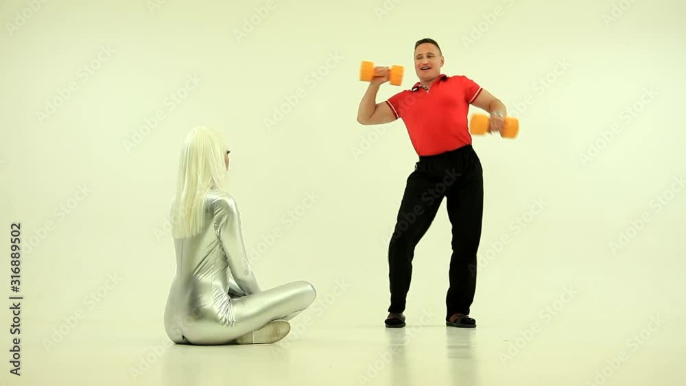 Robot girl and man doing physical exercises with dumbbells watching at girl. Push up. Humor, funny Robot girl and man doing physical exercises with dumbbells watching at girl. Push up. Humor, funny