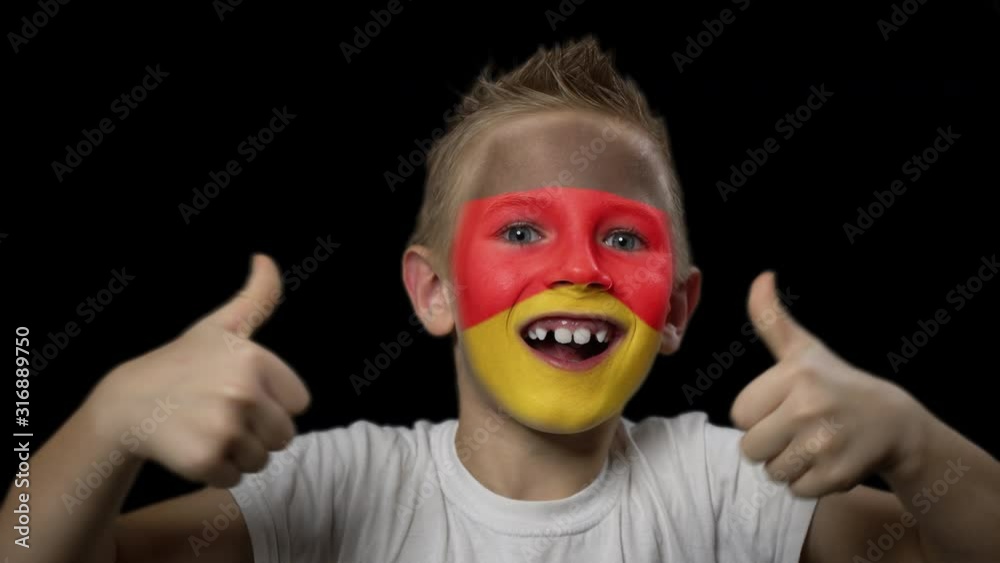 Happy boy rejoices victory of his favorite team of Germany. A child with a face painted in national colors. Portrait of a happy young fan. Joyful emotions and gestures. Victory. Triumph. Happy boy rejoices victory of his favorite team of Germany. A child with a face painted in national colors. Portrait of a happy young fan. Joyful emotions and gestures. Victory. Triumph.