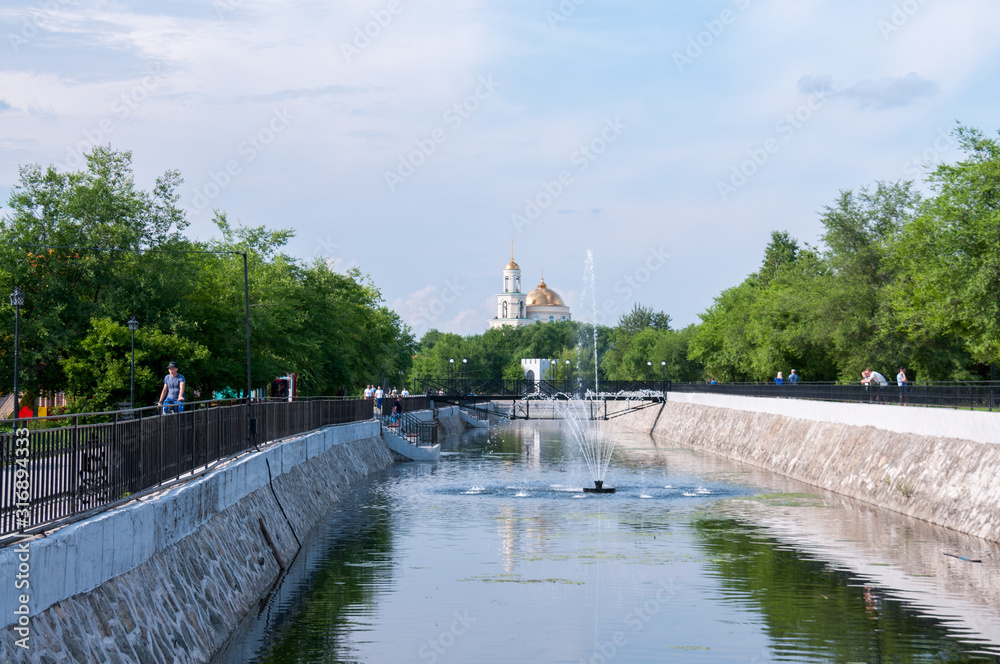 Russia, Blagoveshchensk, July 2019: fountain on the pond in the Park of friendship in the city of Blagoveshchensk in the summer, in the distance Church